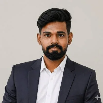 Professional headshot of a man with dark hair and a beard, wearing a navy blazer and white shirt against a light background with a neutral expression.
