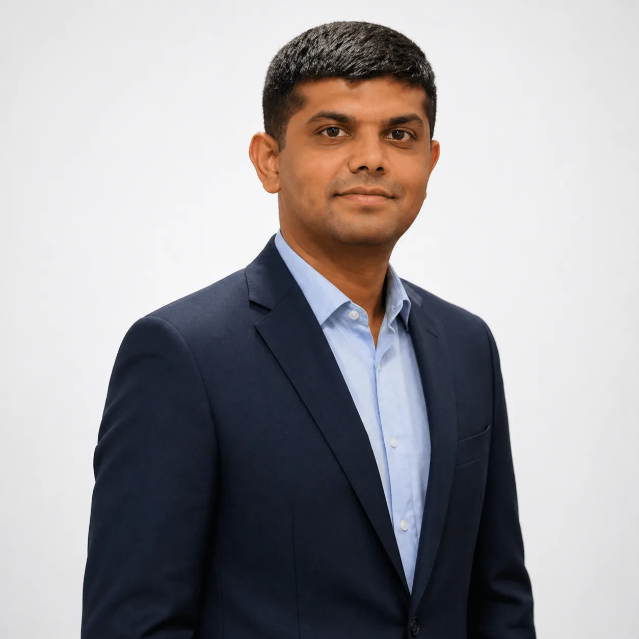 Professional headshot: man in a navy suit and light blue shirt against a neutral background, looking at the camera.